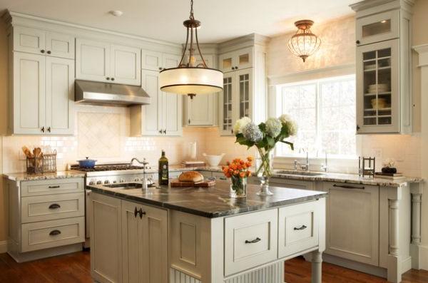 Large single pendant light above a small kitchen counter looks like a modern chandelier